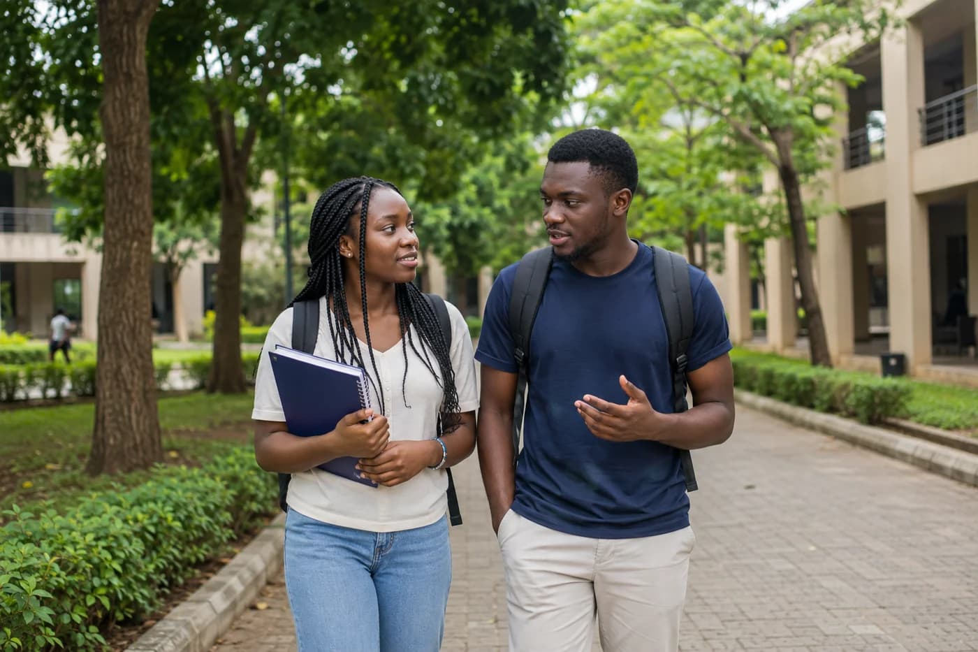 Two students walking and talking on a leafy university campus